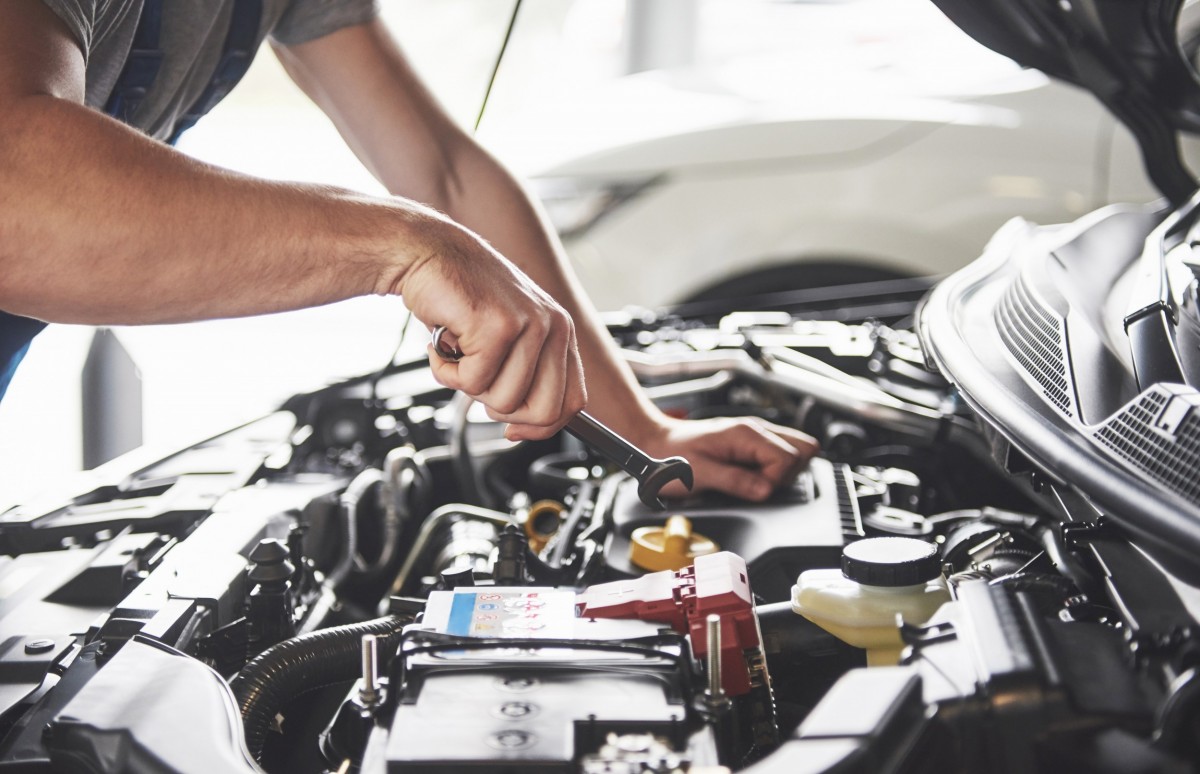 man working on car with hood up 