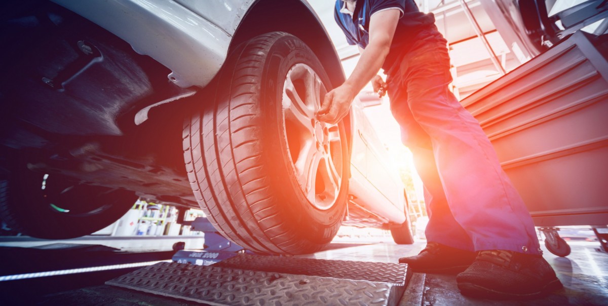 mechanic messing with a tire on a lifted car