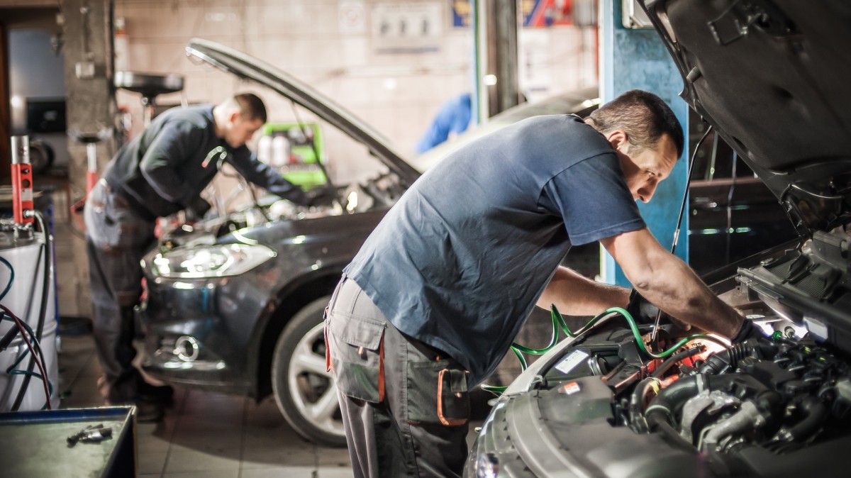 two men working under hood of two different cars