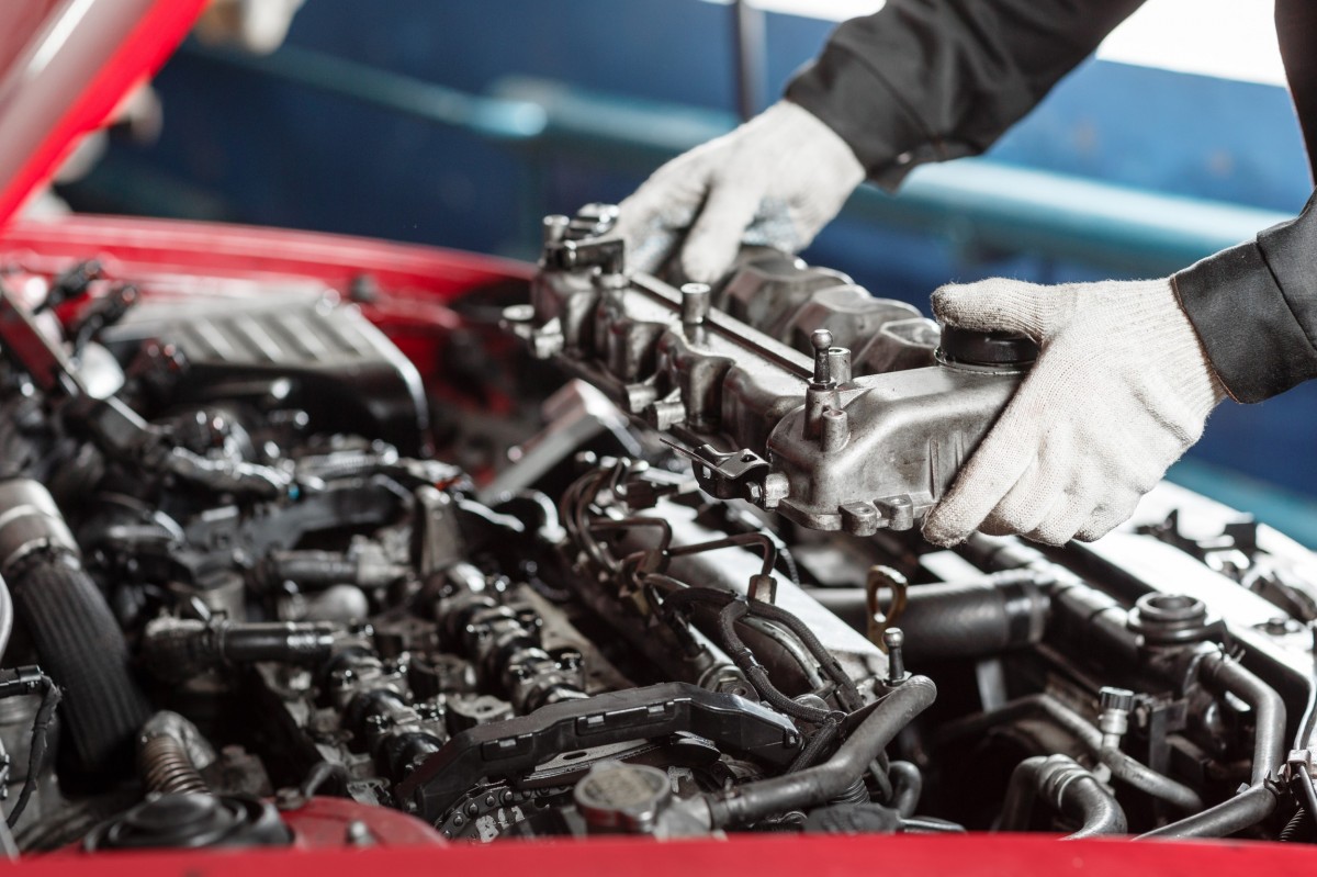 Mechanic taking apart of an engine out from under the hood